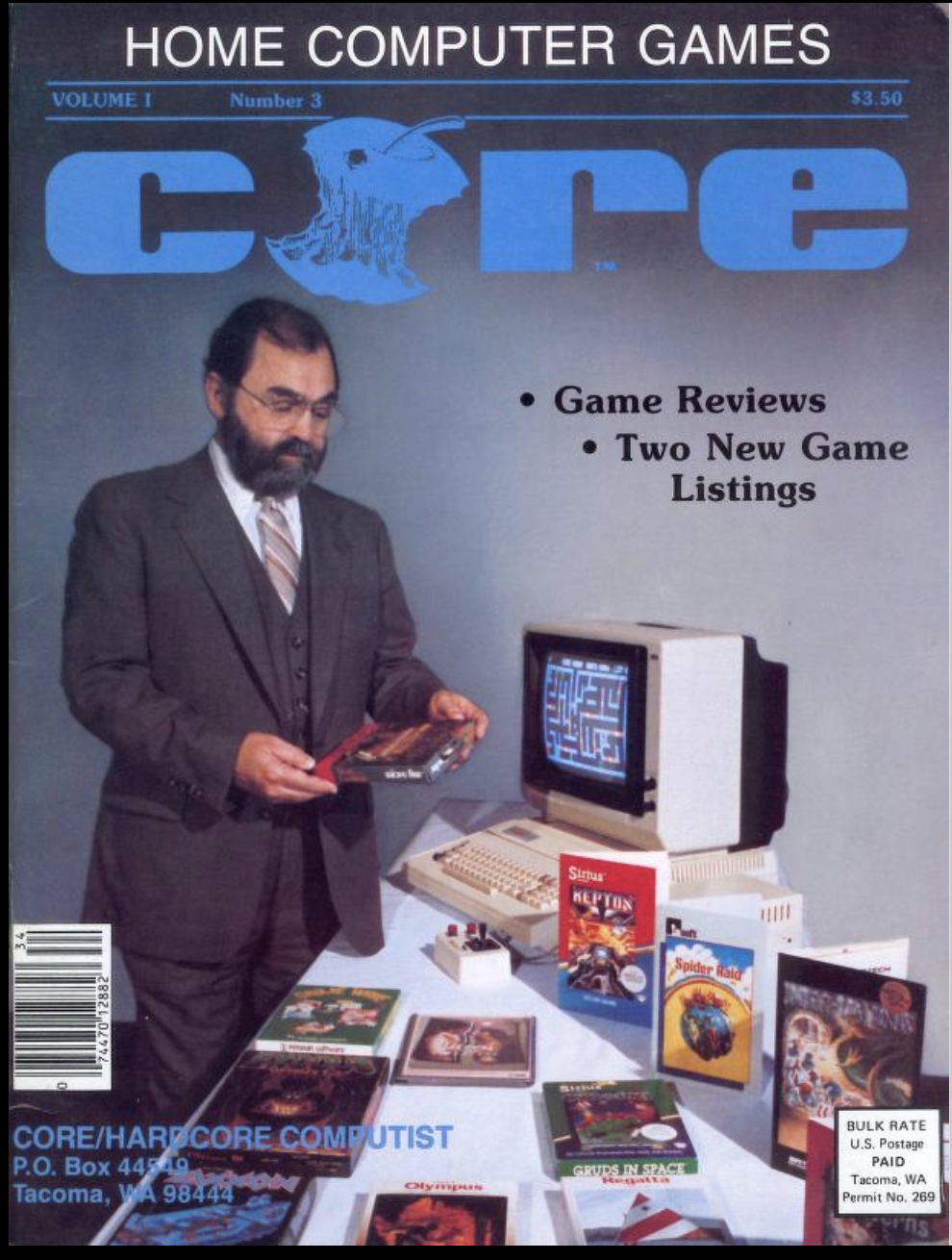 A magazine called Core showing a suited and bearded man contemplating one of a number of boxes of computer software. The rest are laid out on a table with a computer and monitor.
